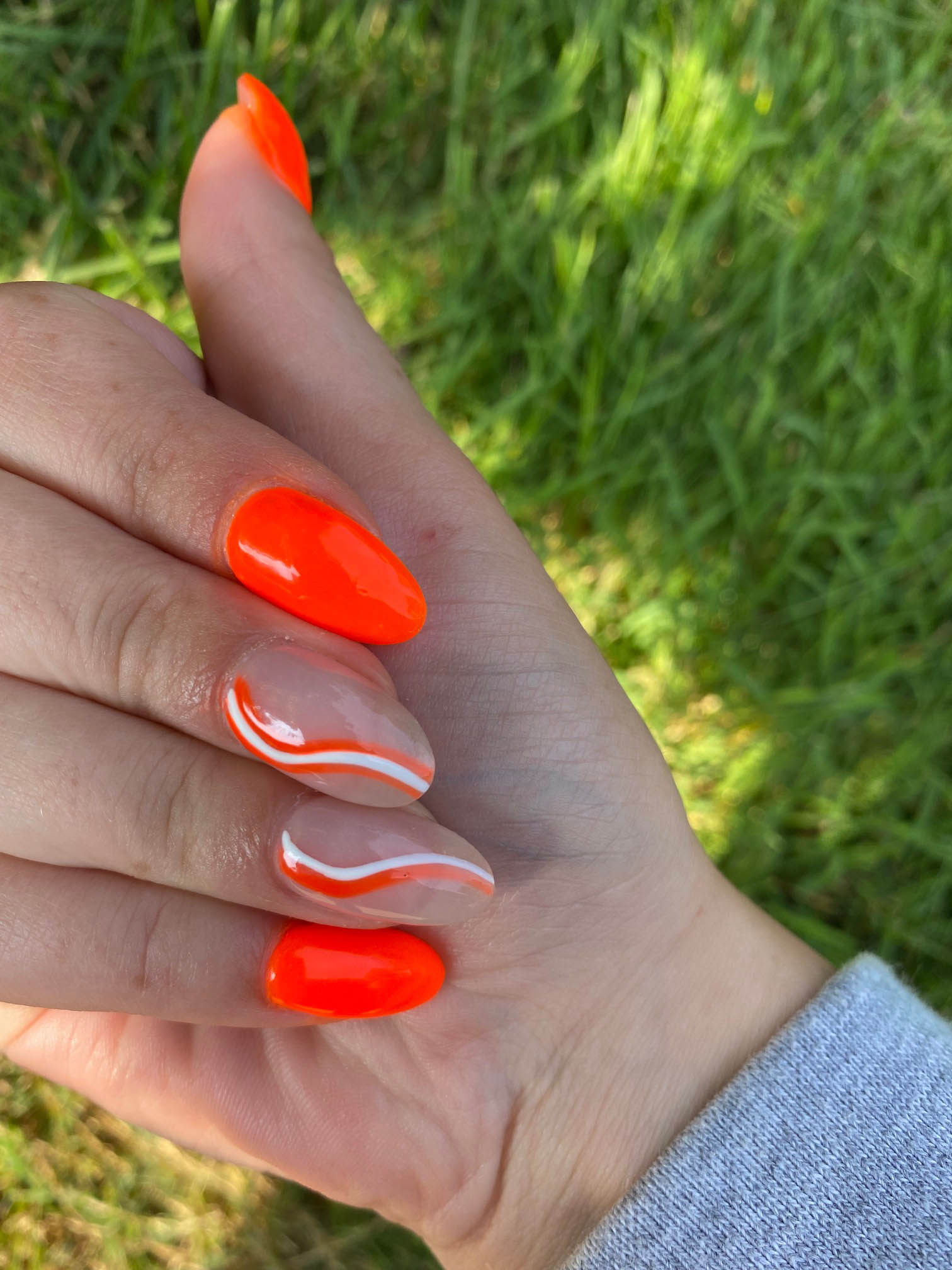 Bright Orange Nails With White Swirls Design Inspo