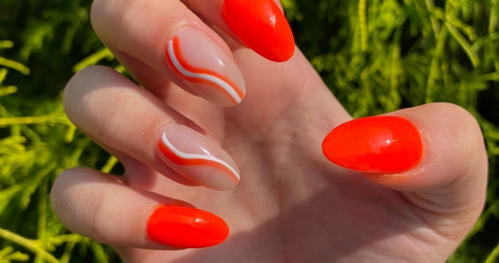 bright orange nails with white swirls nail design idea