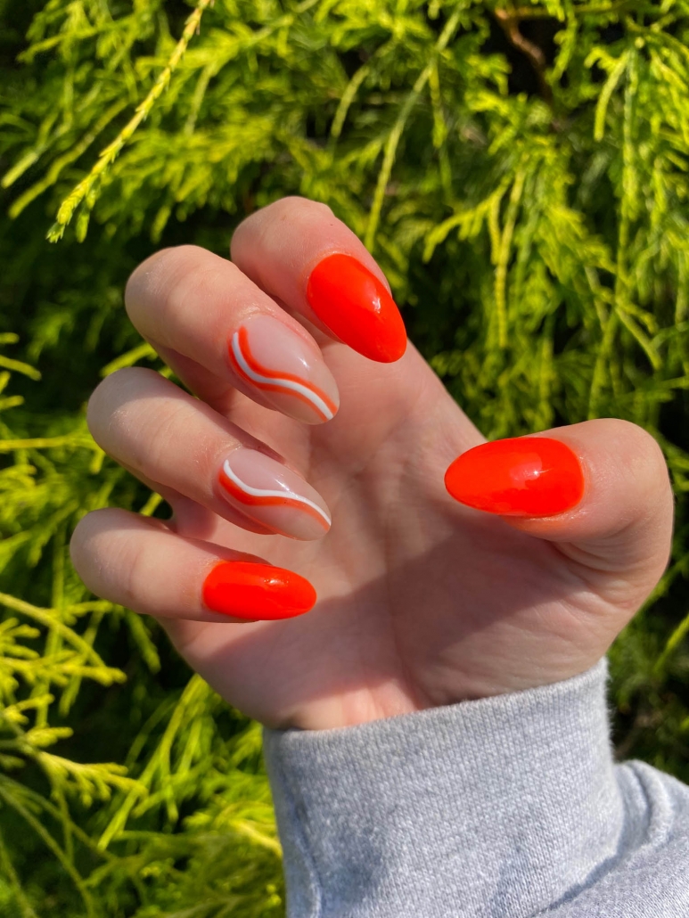 bright orange nails with white swirls nail design idea