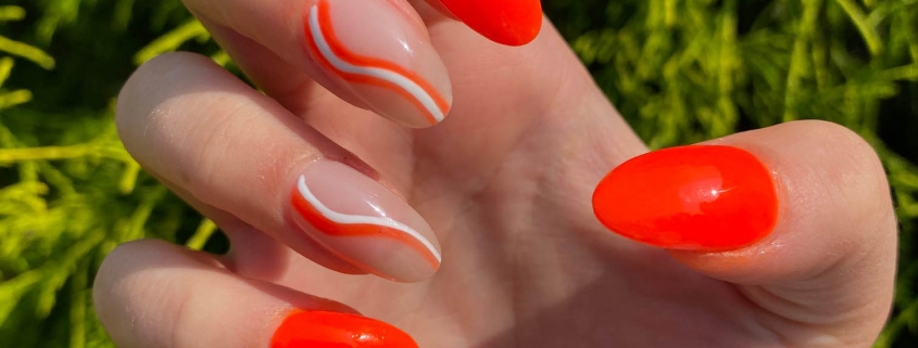 bright orange nails with white swirls nail design idea